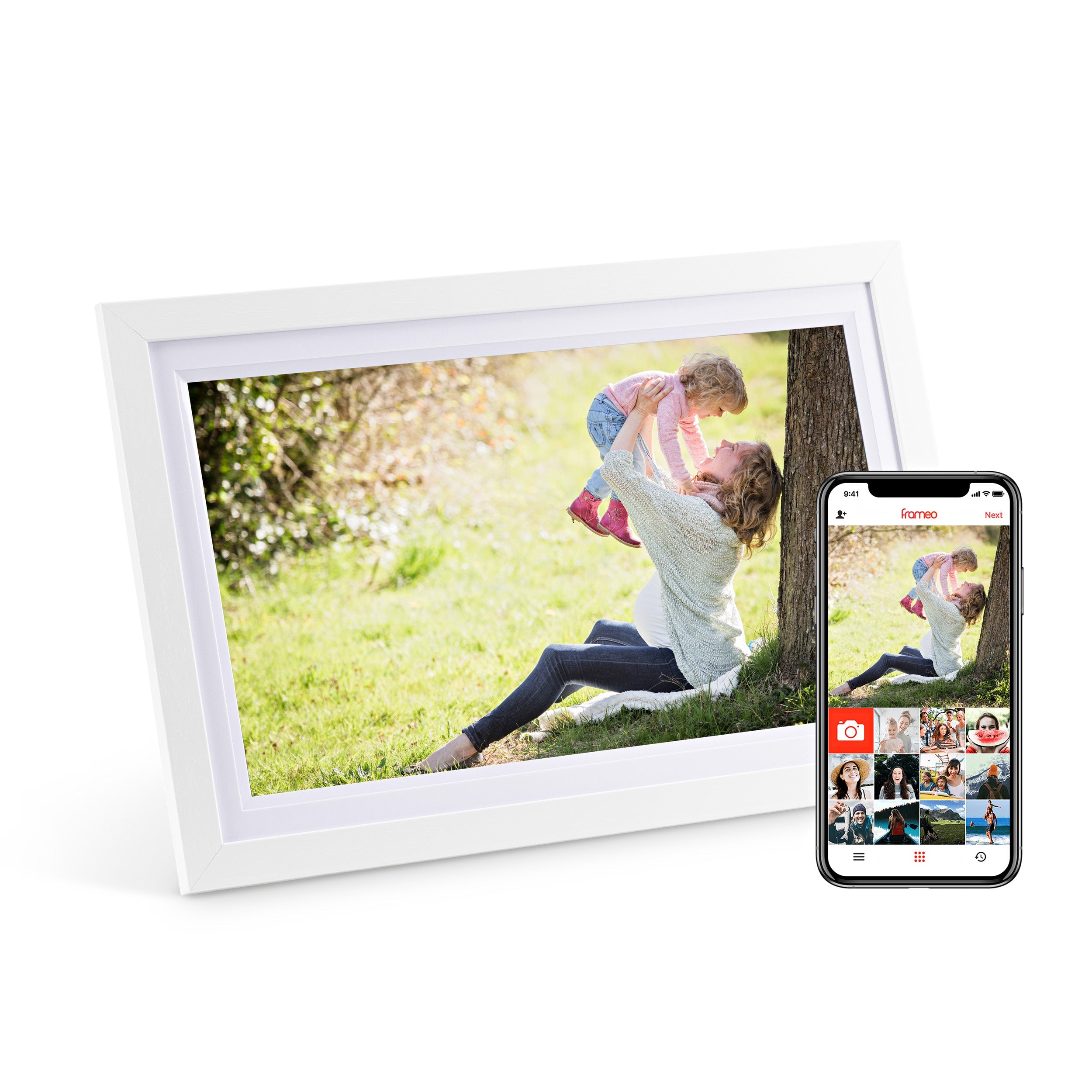 White digital photo frame displaying a photo of a woman playing with a child outdoors, beside a smartphone showing the companion app interface.